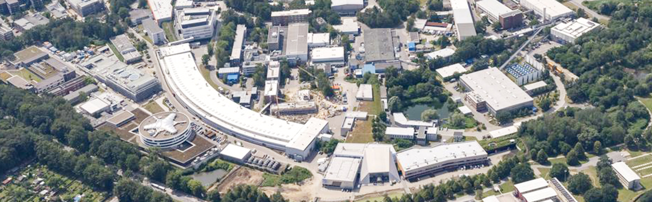 This picture shows an aerial view of the PIER Hamburg buildings in Science City Bahrenfeld. You can see different, large houses and halls and trees as well as groups of trees.